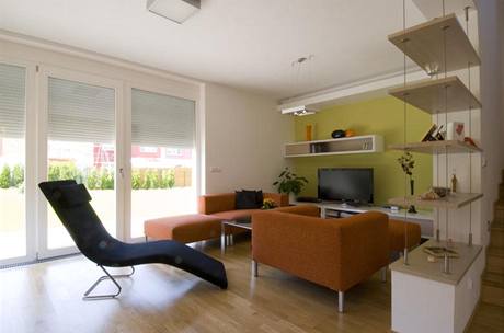 Relaxační část obývacího pokoje designéři oddělili od schodiště policemi zavěšenými na ocelových lankách Relaxační část obývacího pokoje designéři oddělili od schodiště policemi zavěšenými na ocelových lankách