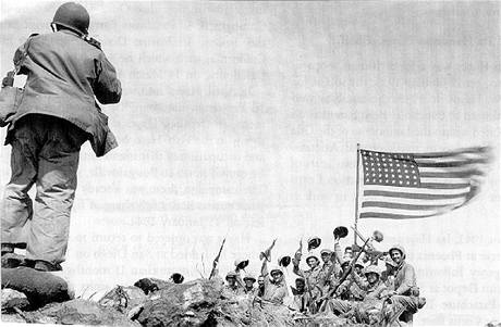 Fotograf Joe Rosenthal pořizuje snímek radujících se amerických vojáků na vrcholu Mt. Suribachi. (23. února 1945) Fotograf Joe Rosenthal pořizuje snímek radujících se amerických vojáků na vrcholu Mt. Suribachi. (23. února 1945)