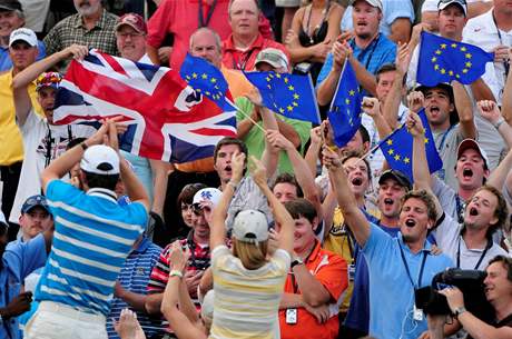 Justin Rose děkuje fanouškům svého týmu - britská vlajka a zástavy Evropské unie symbolizují vývoj Ryder Cupu. Justin Rose děkuje fanouškům svého týmu - britská vlajka a zástavy Evropské unie symbolizují vývoj Ryder Cupu.