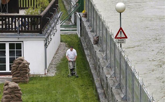 Muž seká trávník za protipovodňovou stěnou v dolnorakouském městečku